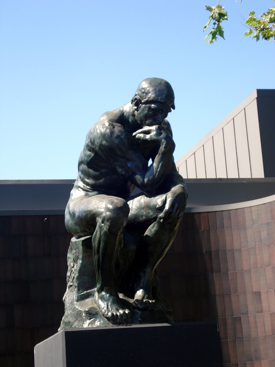 A bronze cast of The Thinker by Auguste Rodin, showing a muscular figure deep in thought