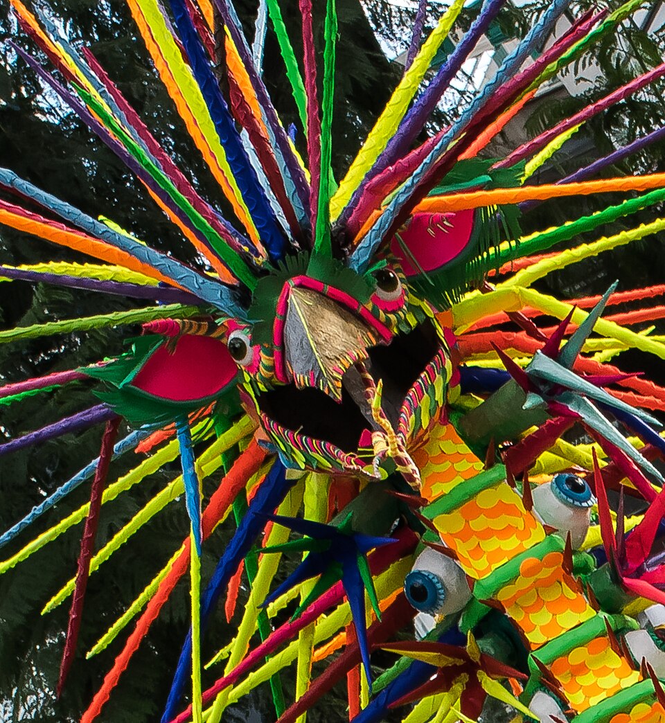 A giant colorful alebrije creature with spiky rainbow-colored spines at a parade in Mexico City
