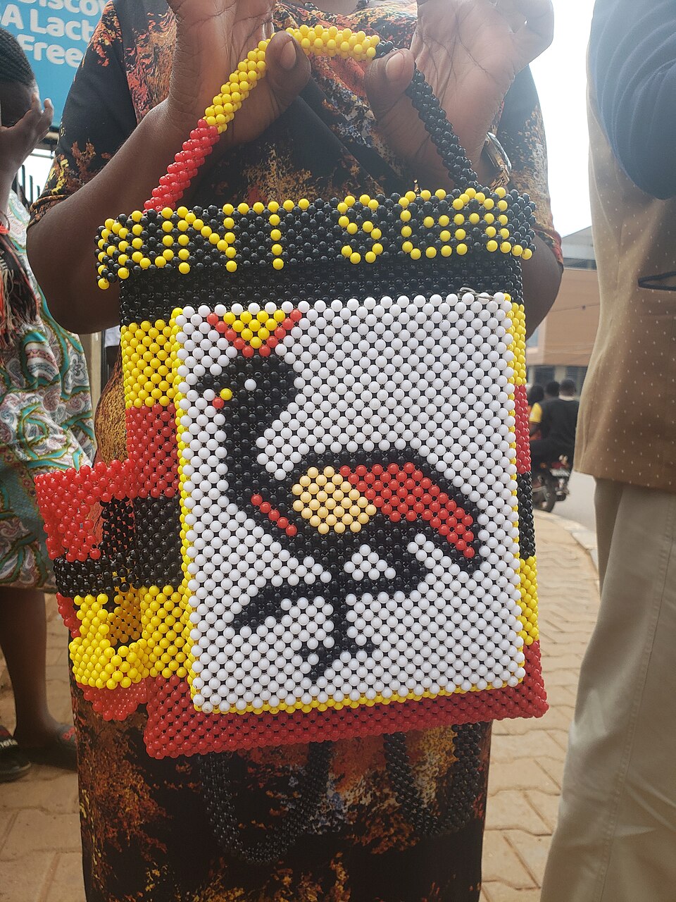 A handmade beaded handbag featuring a colorful bird design made from glass beads