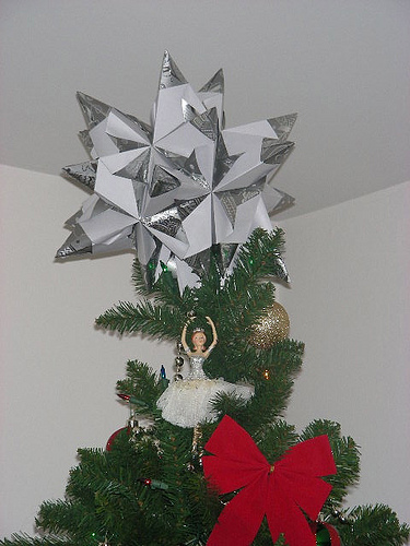 A modular origami star made from silver foil paper, showing how many folded units fit together