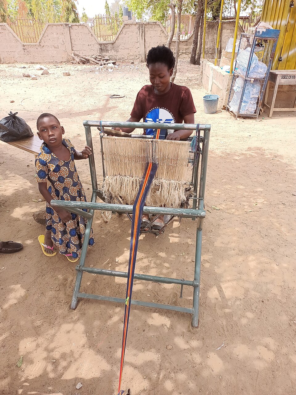 A woman weaving kente cloth on a traditional loom in Ghana