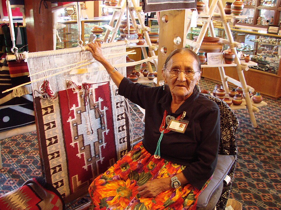 A Navajo weaver creating a traditional rug with geometric patterns on a loom