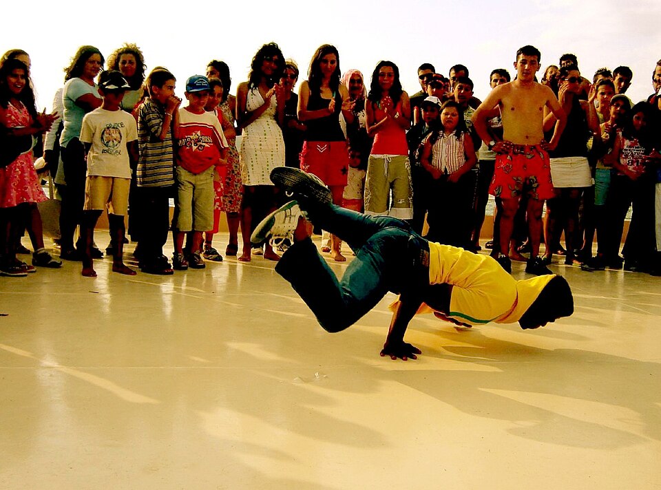 A b-boy performing a breakdancing floor move while a crowd watches