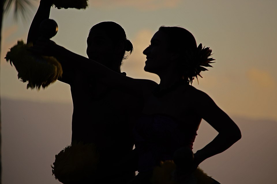 Silhouettes of hula dancers performing against a sunset sky in Hawaii