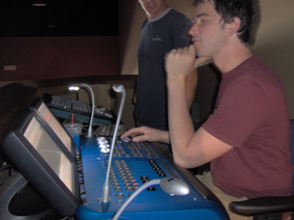 A technician operating a lighting control console during a theater production