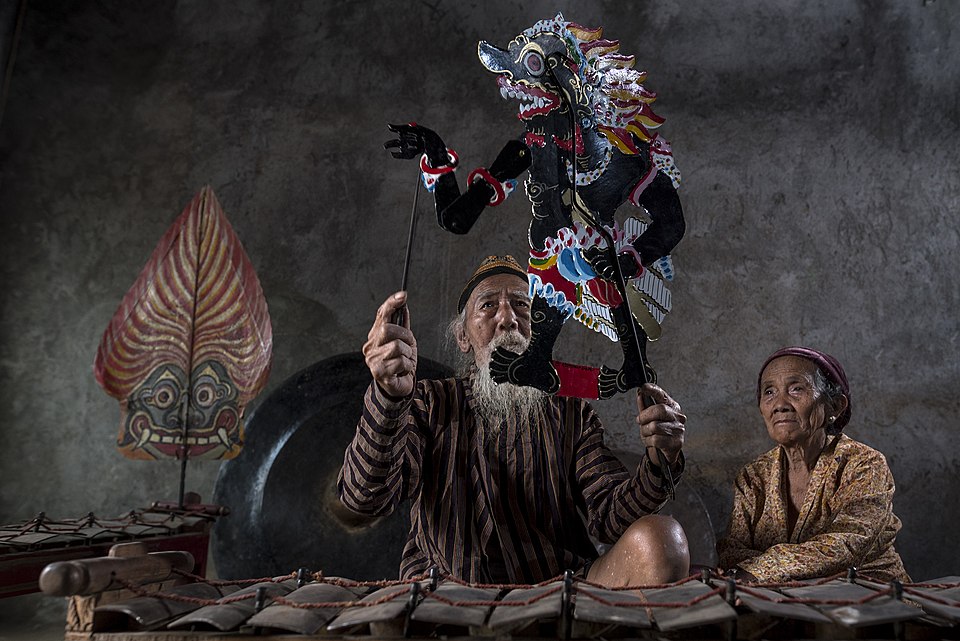 An Indonesian puppeteer holding a traditional wayang kulit shadow puppet