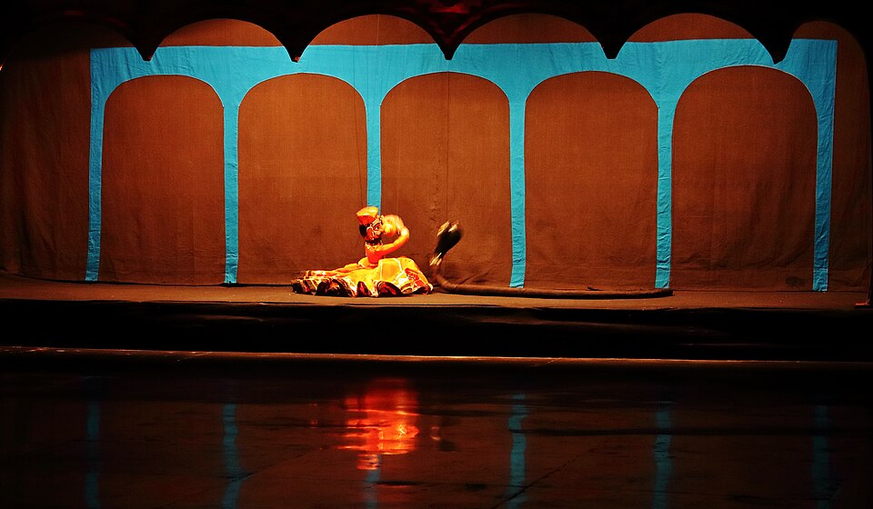 A colorful Rajasthani Kathputli marionette performing on a stage, controlled by strings from above