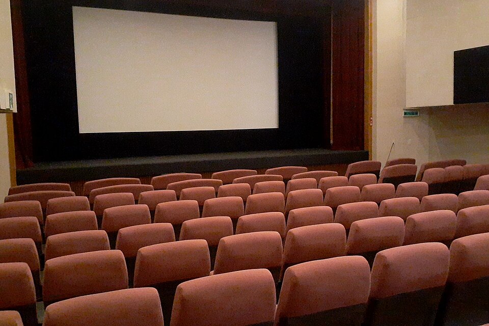 The interior of a movie theater with rows of seats facing a large screen