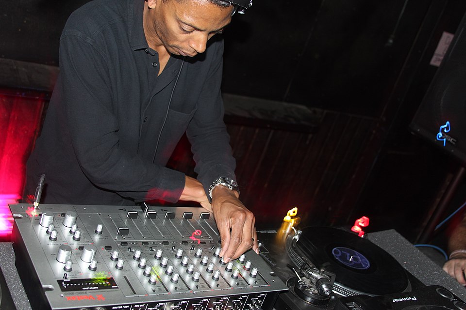 A DJ mixing vinyl records on turntables and a mixer board