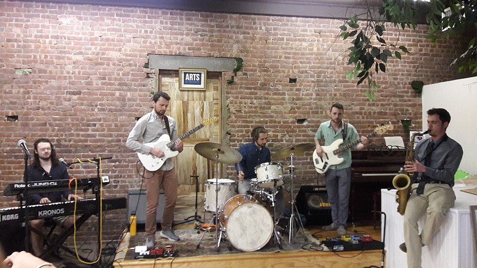 A jazz ensemble performing live with keyboards, guitar, drums, bass, and saxophone