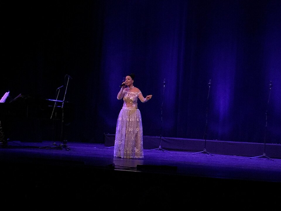 An opera singer performing on stage in a flowing white dress