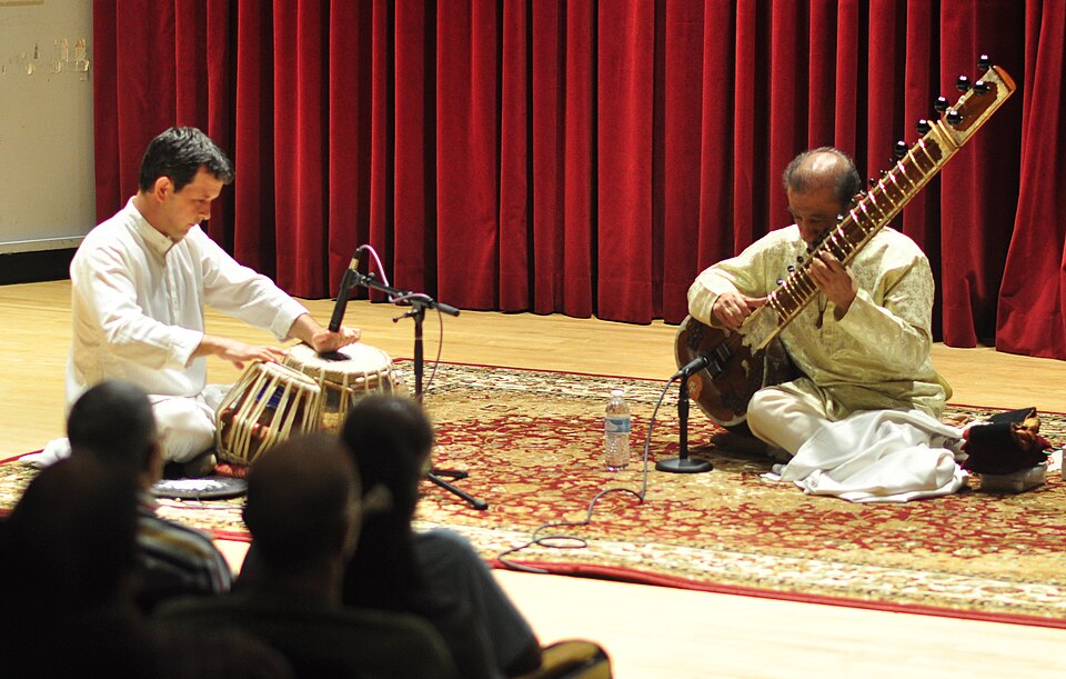 A sitar player and tabla player performing Indian classical music on stage