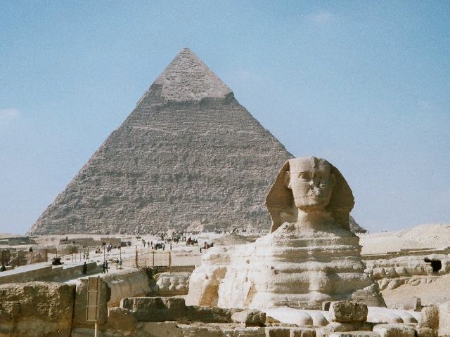 The Great Sphinx of Giza sits in front of a pyramid in the Egyptian desert
