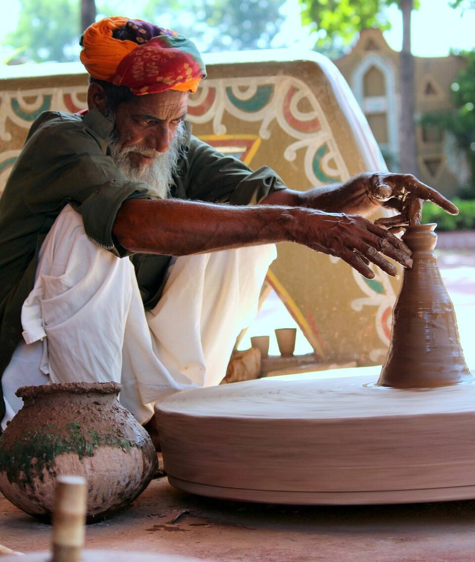 A potter shaping a clay pot on a spinning potter’s wheel in India