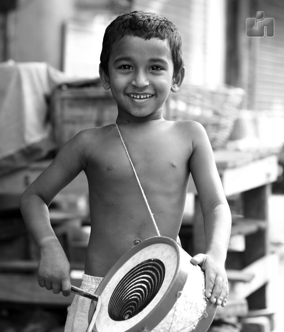 A smiling child playing a drum in India