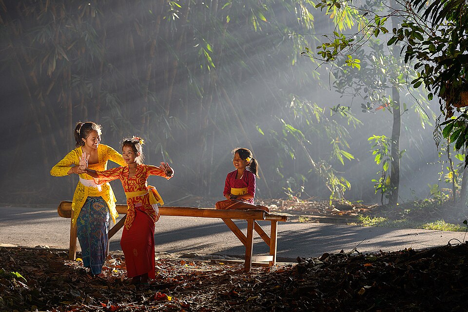 Children learning a traditional dance in Bali with sunlight streaming through bamboo trees
