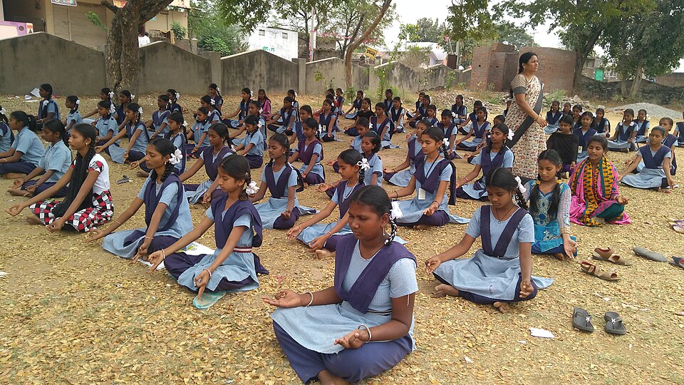 School children doing yoga stretches together outside