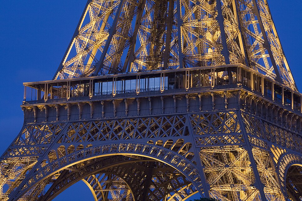 The Eiffel Tower lit up in the evening showing its iron structure