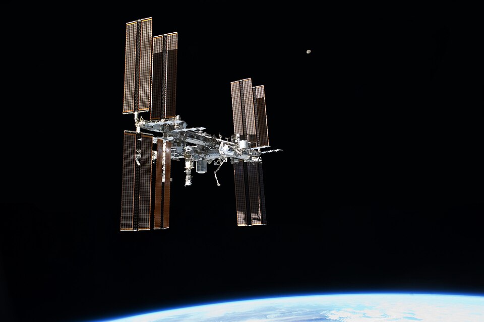 The International Space Station floating above Earth with its large solar panels spread out